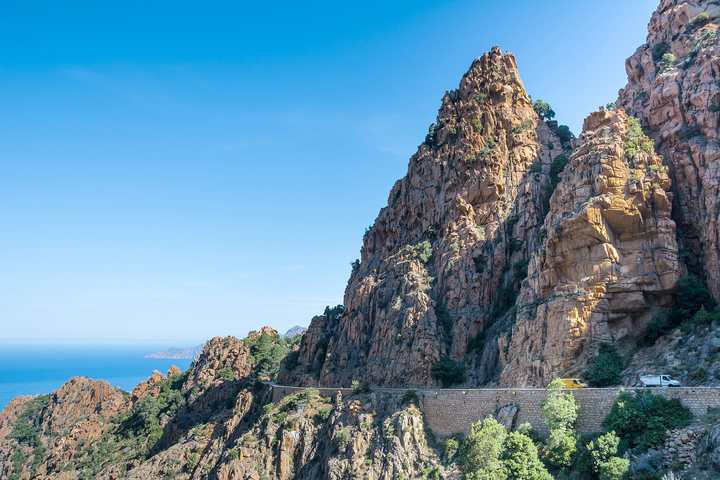 The D81 coast road cut into the red cliffs of the Calanques de Piana, Corsica