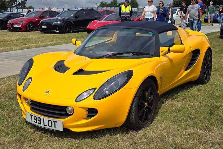 A yellow Lotus Elise 111R Series 2 parked on grass