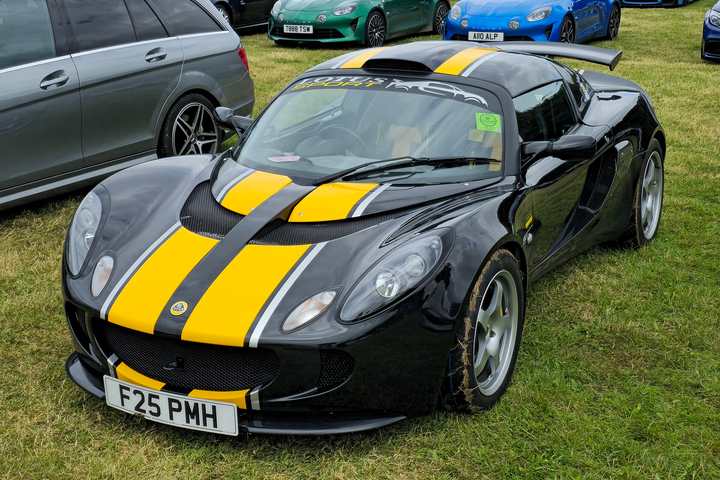 A black Lotus Exige S Series 2 with yellow stripes