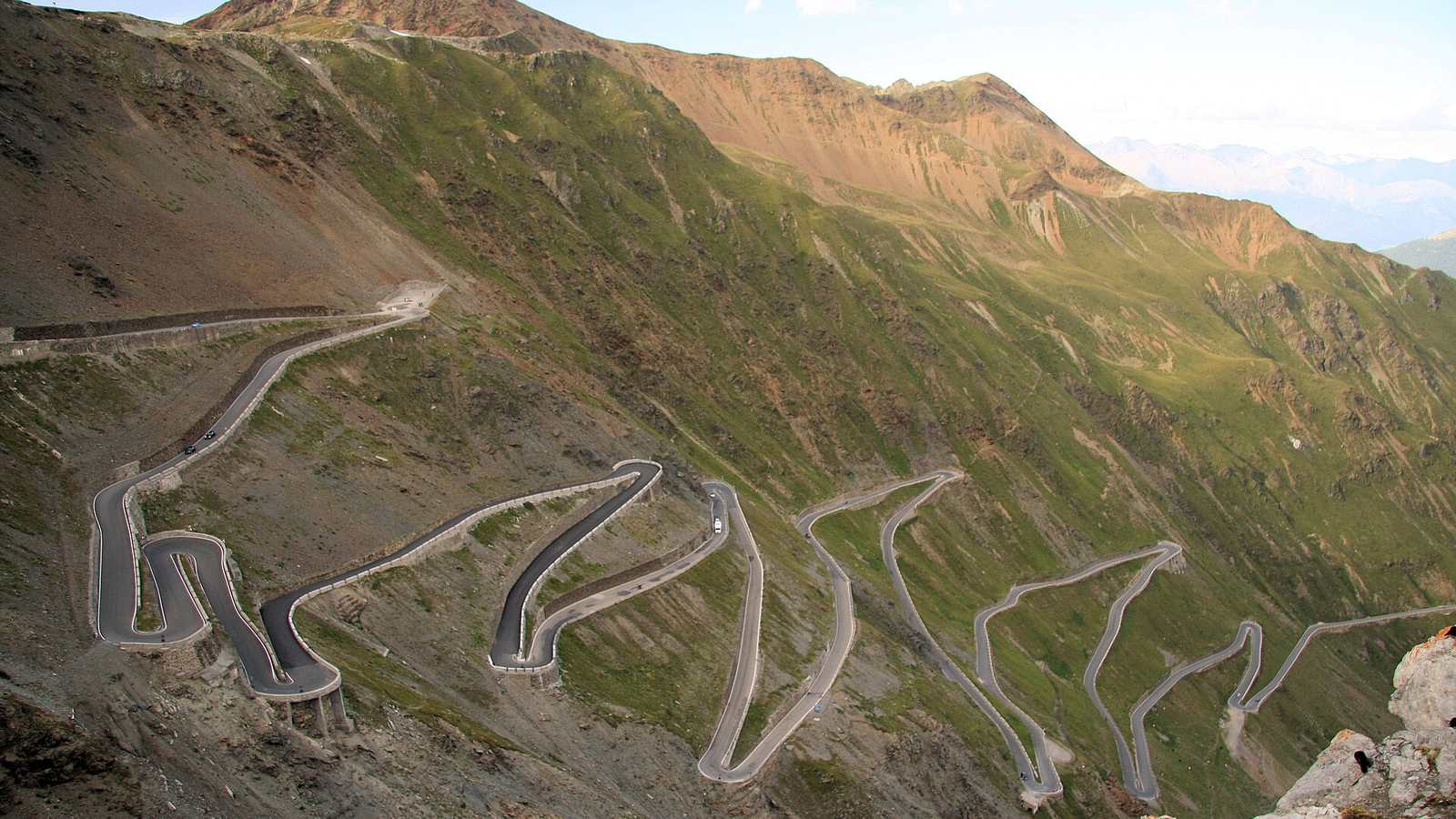 The stacked hairpin bends of the Stelvio Pass climbing the valley wall above Trafoi